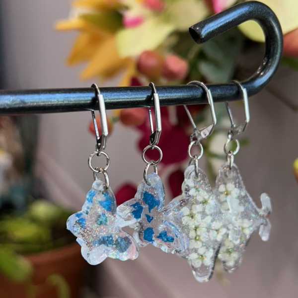 Three glittery fish-shaped earrings hang from a black rod.