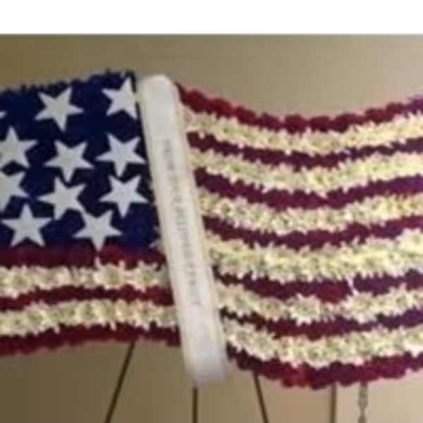 Waving American flag design made of red, white, and blue flowers on a standing easel.
