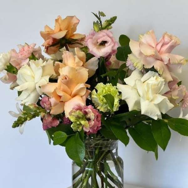 Mixed pastel flowers arranged in a clear glass vase