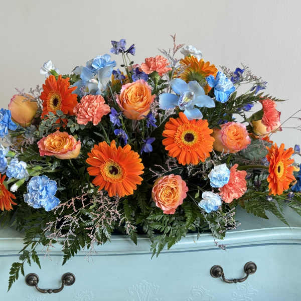 Bright mixed bouquet with orange gerberas, peach roses, and blue flowers