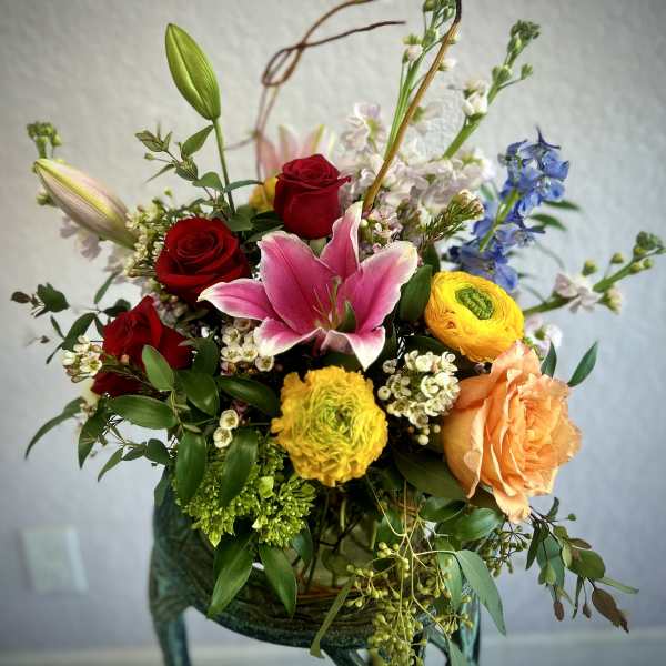 Mixed bouquet with red roses, pink lily, and yellow blooms in a vase