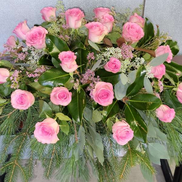 Pink roses arranged with greenery in a low floral display