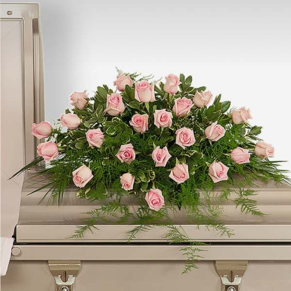 Pink rose spray arranged on top of a casket