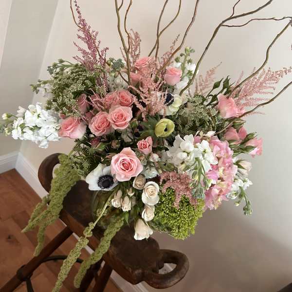 Large pink and white floral arrangement with tall branches in a vase