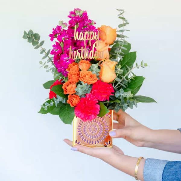 Handheld birthday flower arrangement in a gold box with a "happy birthday" topper