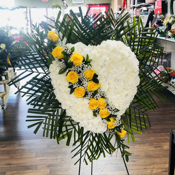 Heart-shaped white floral spray with yellow roses and palm fronds