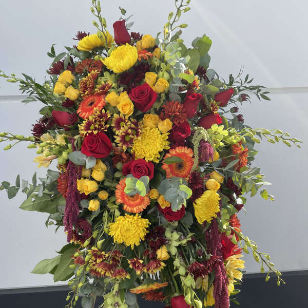 Large standing floral spray with red, yellow, and orange blooms on an easel