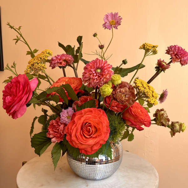 Bright mixed bouquet in a mirrored round vase