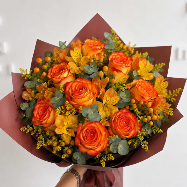 Bouquet of orange roses and yellow alstroemeria with burgundy wrap