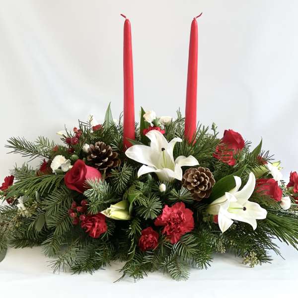 Holiday centerpiece with red candles, white lilies, and pinecones