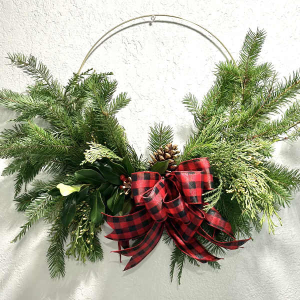 Evergreen holiday swag with a red plaid bow on a metal hanger