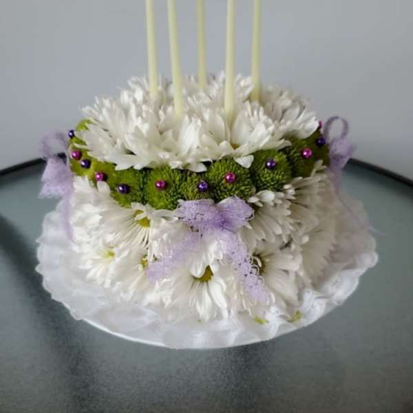 White floral cake with five tall candles and purple ribbon accents