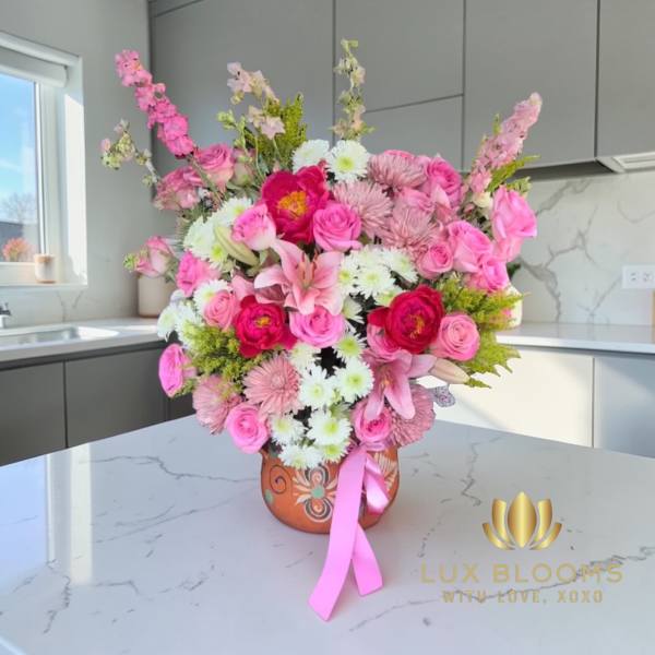 Pink and white mixed flower arrangement in a decorative vase with a ribbon