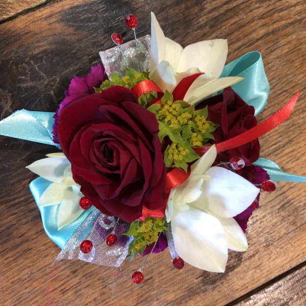 Small corsage with red roses and white flowers on blue ribbon