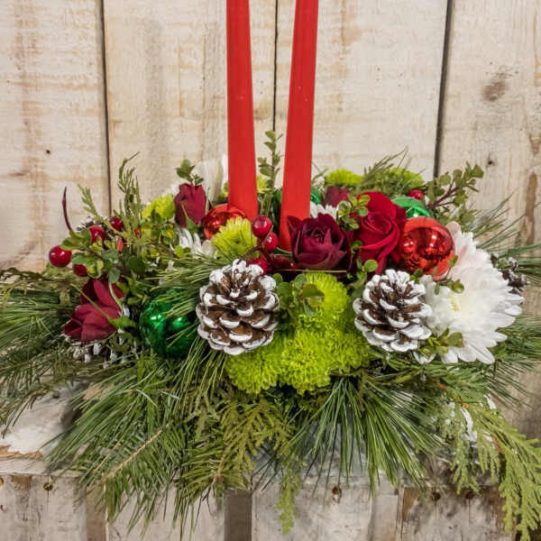 Holiday centerpiece with red candles, roses, and pinecones