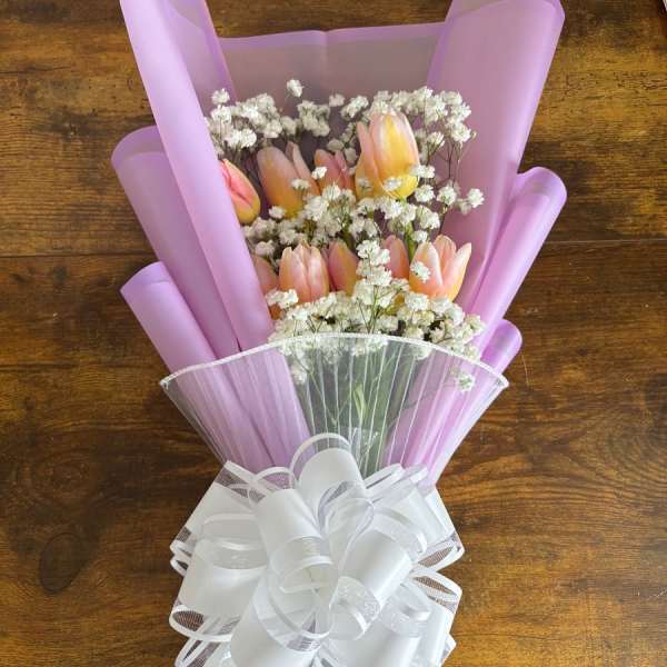 Pink tulip bouquet with white filler flowers and a large white bow