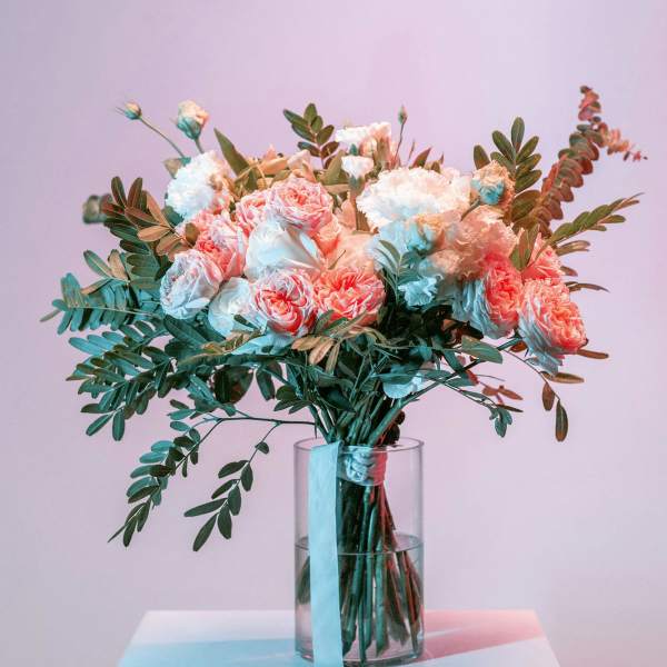 Pink and white bouquet in a clear glass vase with trailing greenery