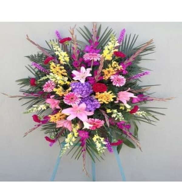 Large standing spray of mixed pink, purple, yellow, and white flowers