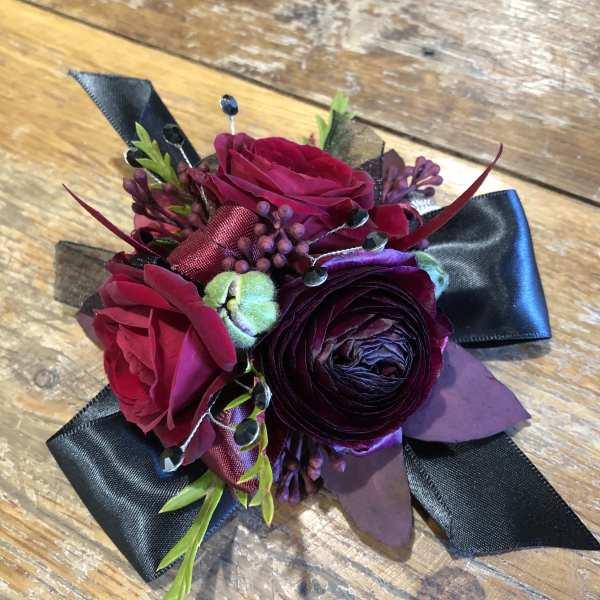 Small corsage with deep pink and purple flowers and black ribbon