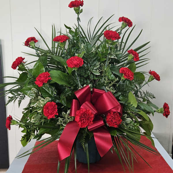 Red carnations in a vase with a large red ribbon