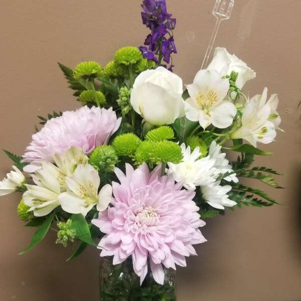 Mixed bouquet of pink, white, and purple flowers in a glass vase