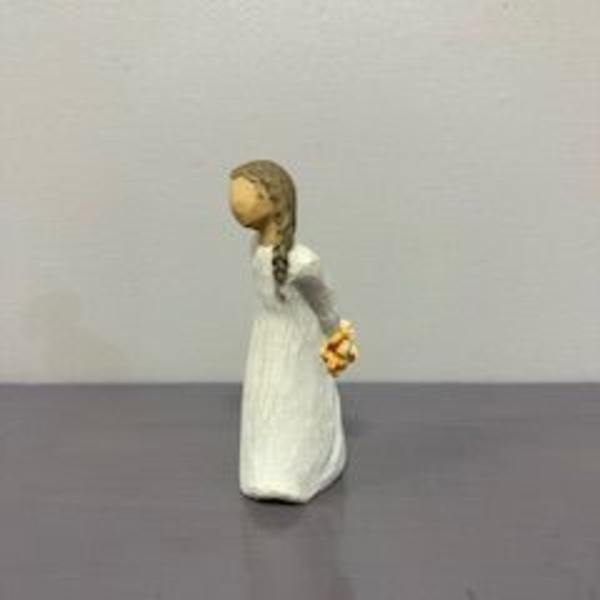 Small figurine of a girl in a white dress holding flowers behind her back