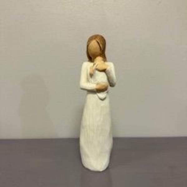 Small figurine of a girl in a white dress holding a teddy bear