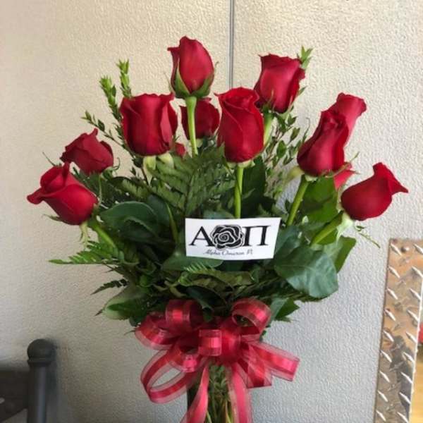 Bouquet of red roses in a clear glass vase with a pink ribbon