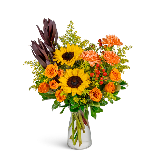 Bouquet of sunflowers, orange roses, and carnations in a clear glass vase