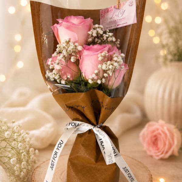 Bouquet of pink roses and white baby's breath wrapped in brown paper