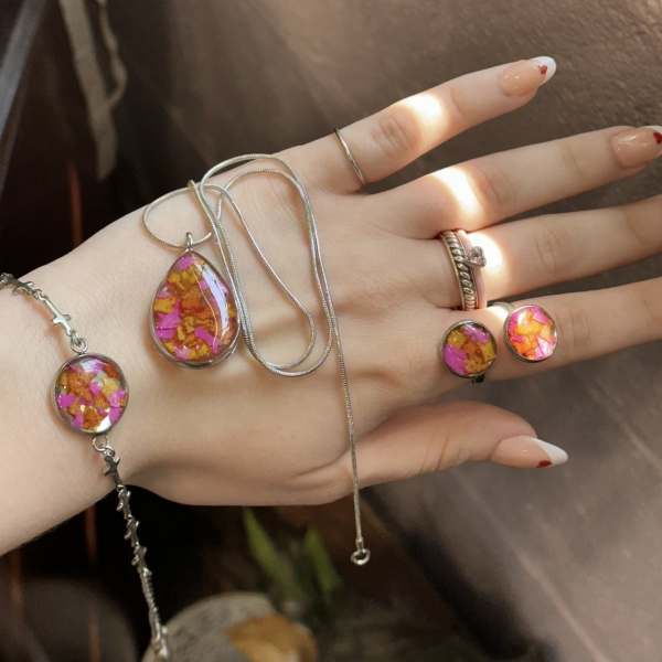 Hand wearing colorful resin jewelry with silver chains and rings