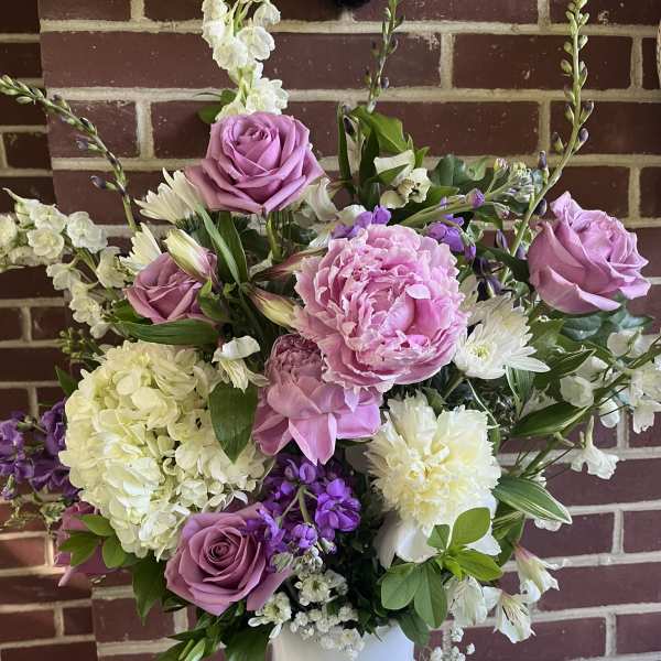 Pink roses and peonies in a white vase with white and purple flowers