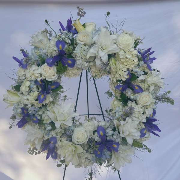 White and purple floral wreath on a stand