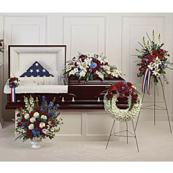 Patriotic funeral floral set with red, white, and blue arrangements around a casket