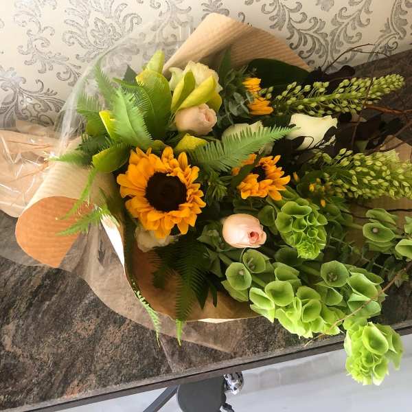 Bouquet with sunflowers, pale roses, and green hydrangea in brown paper