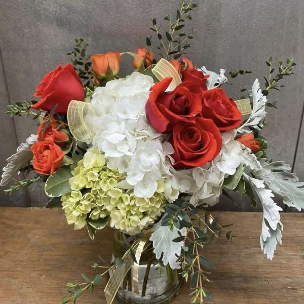 Bouquet of red and orange roses with white hydrangeas in a glass vase