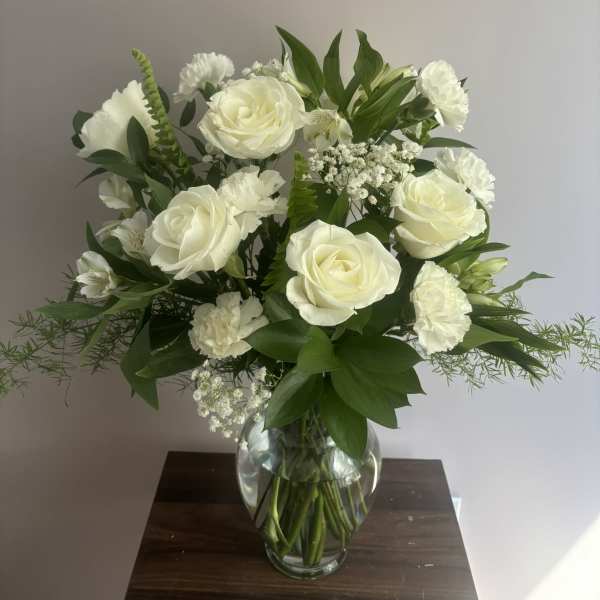 White roses and carnations arranged in a clear glass vase