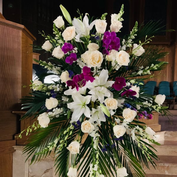 Large standing floral spray with white lilies, roses, and purple orchids