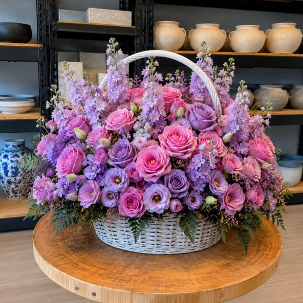 Basket of pink and lavender roses with purple flowers
