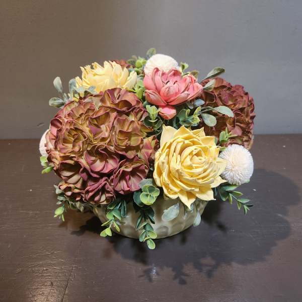 Artificial floral arrangement in a low ceramic bowl with pink, yellow, and white blooms
