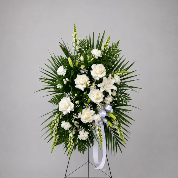 White floral standing spray with roses and lilies on an easel