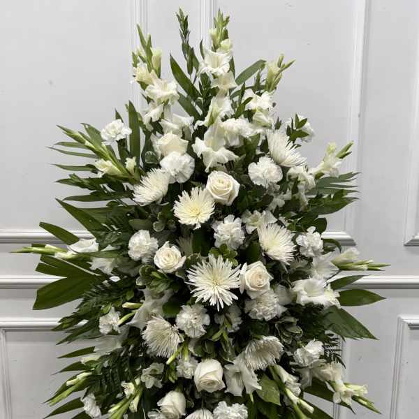 Tall white funeral spray with roses, chrysanthemums, and lilies