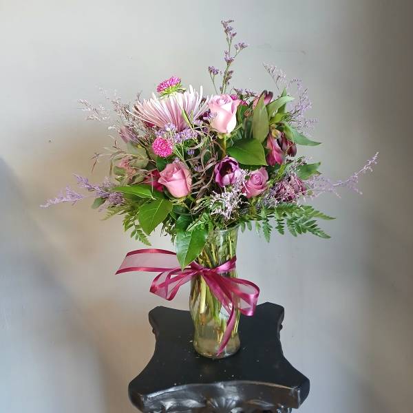 Pink and purple mixed bouquet in a glass vase with a ribbon