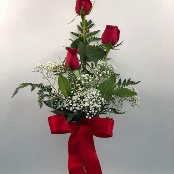 Tall bouquet of red roses with baby's breath in a glass vase and red ribbon