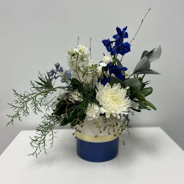 Blue and white floral arrangement in a round blue container
