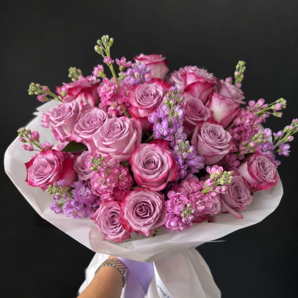 Hand-tied bouquet of pink and lavender roses with small purple filler flowers