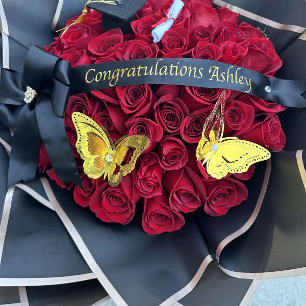Red rose bouquet with a graduation cap and black ribbon reading Congratulations Ashley