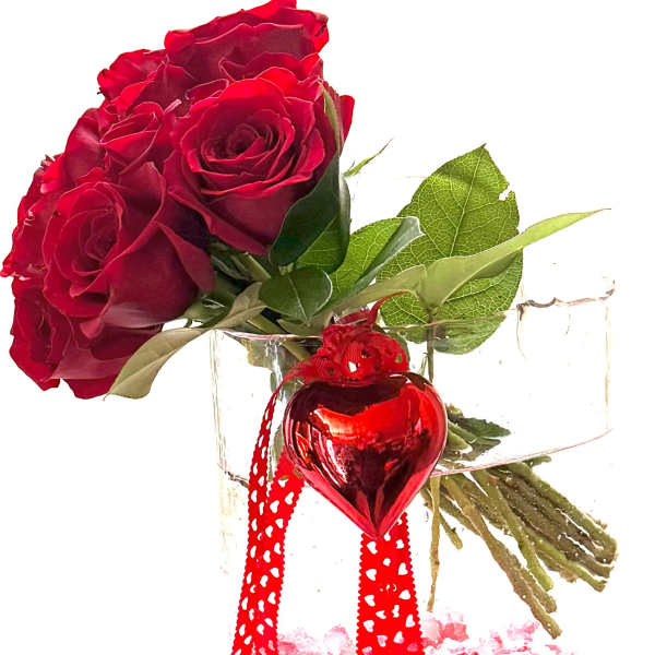 Red roses in a clear glass vase with a red heart ornament