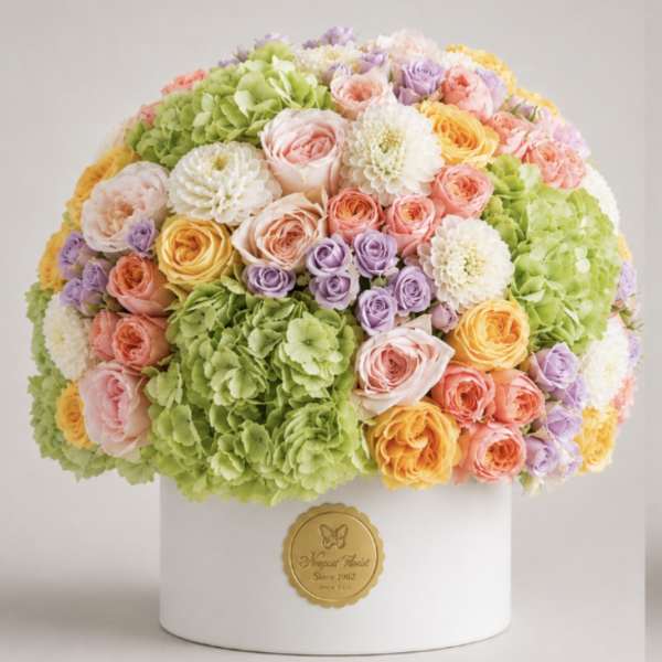 Round bouquet of pastel roses, hydrangeas, and white blooms in a white box