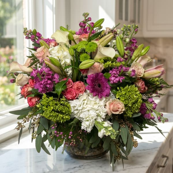 Mixed bouquet of pink, white, and green flowers in a glass bowl vase